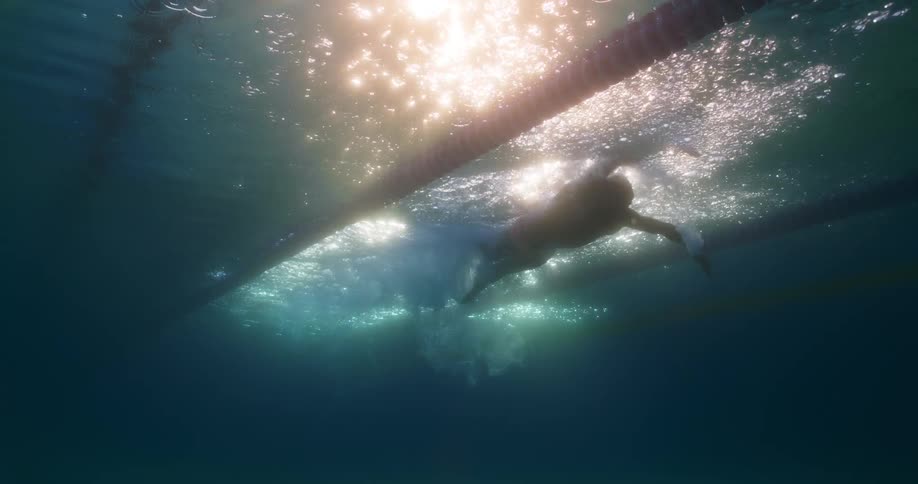 A man is swimming in a lane of an outdoor pool