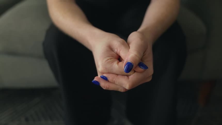 A person is sitting on a couch with blue nail polish