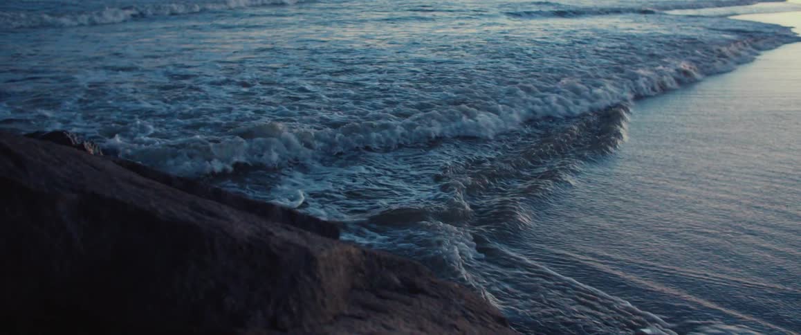 Waves are rolling on the shore near rocks