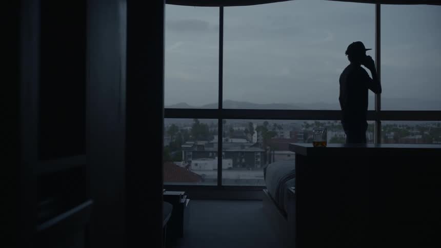Silhouette of man walking across a large window talking on cell phone