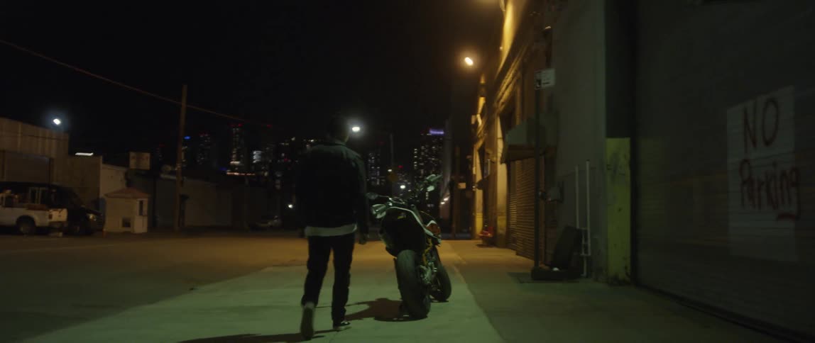 A person walking towards their parked motorycle at night