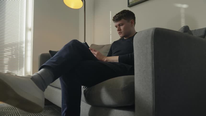 A man is sitting and relaxing indoors on a couch