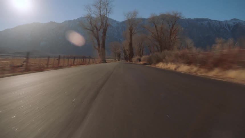 Driving fast on a road in the countryside towards the mountains