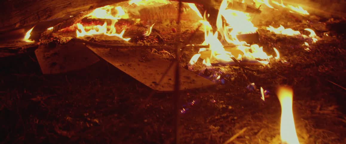 Out of control bonfire consuming big logs and tree trunks outdoors at night