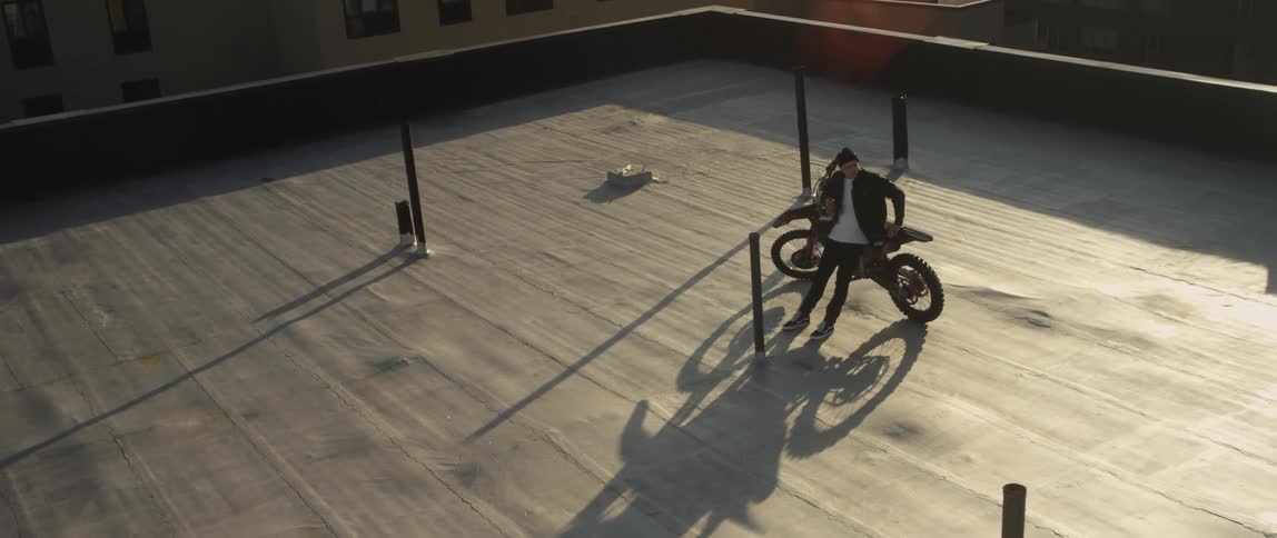 A man leans against his bicycle on the rooftop of a tall building