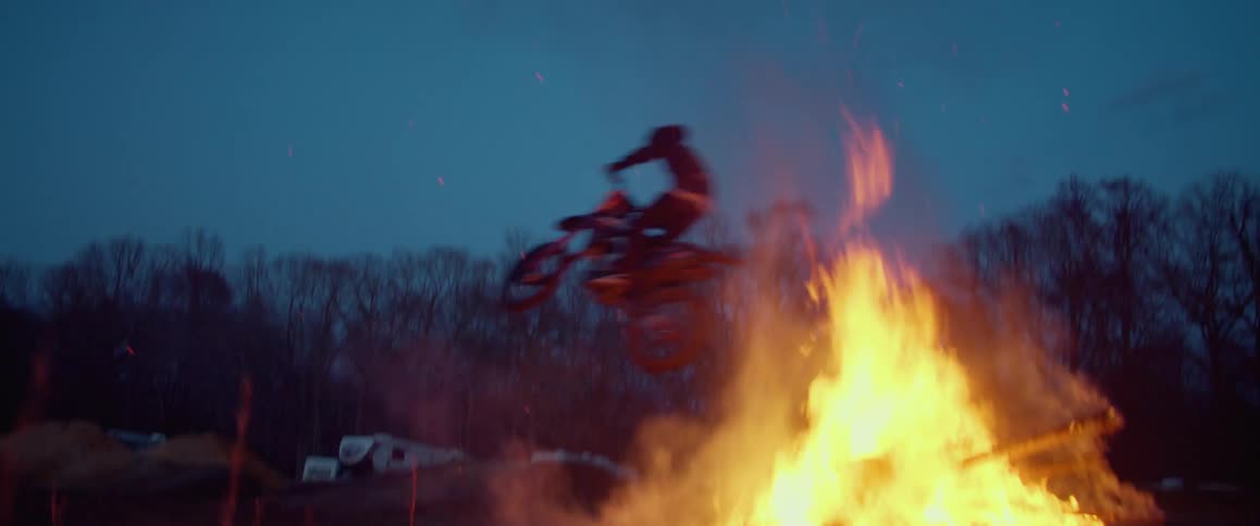 A motorcycle rider leaps over a bonfire