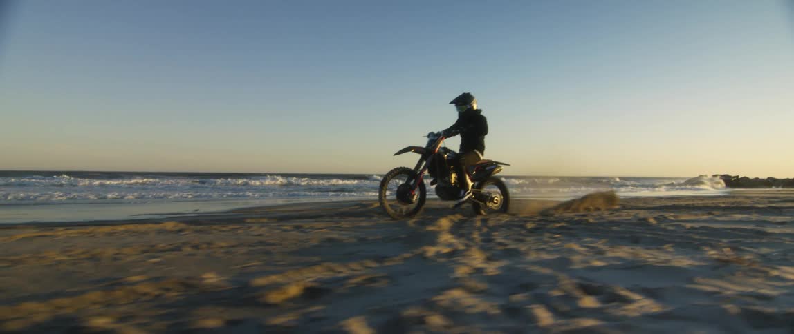 A person rides their dirt bike on the beach