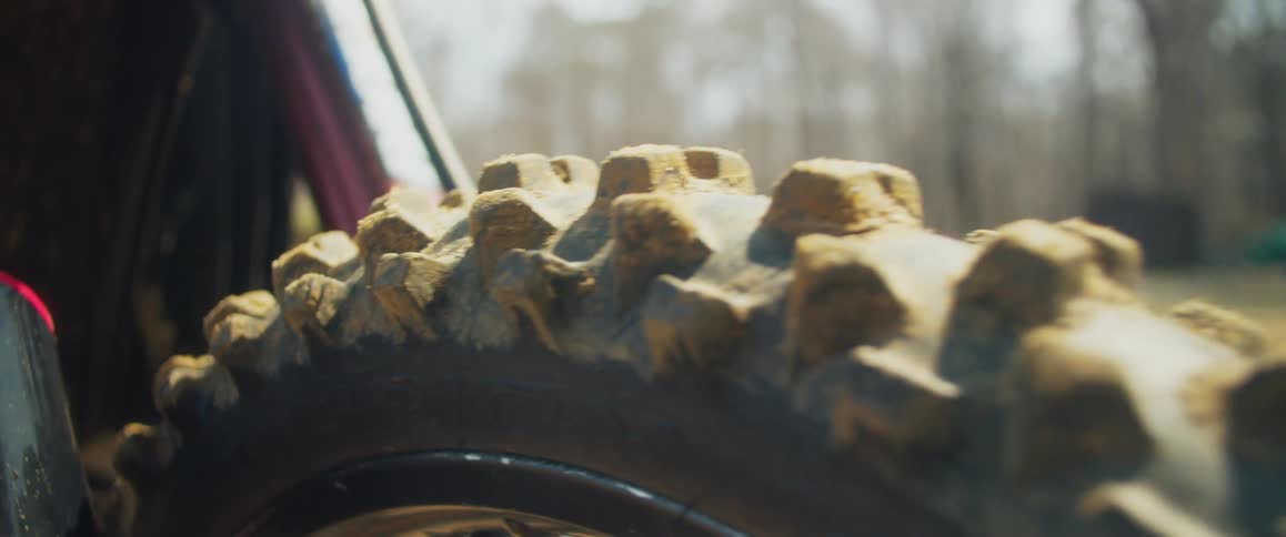 Close up of a motorcycle tire covered in mud outdoors in the wilderness