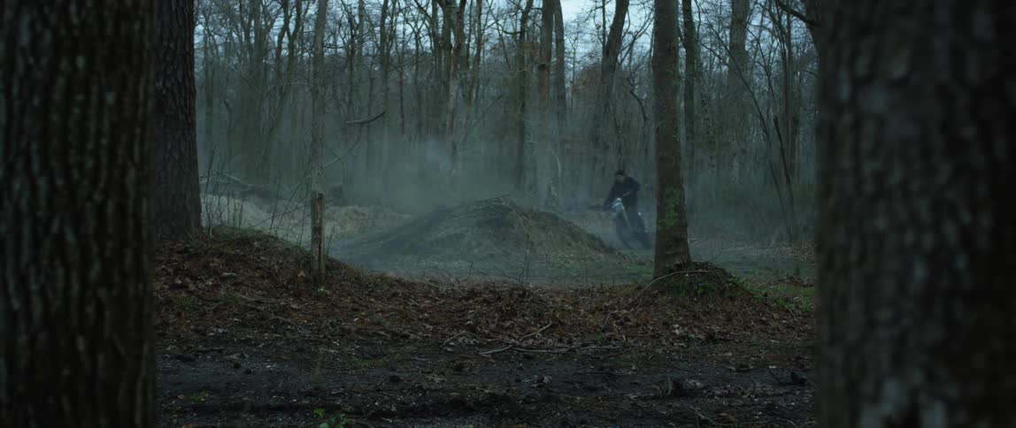 A dirt biker jumps on a hill in the forest