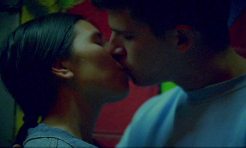 A couple make out while standing near a wall outdoors