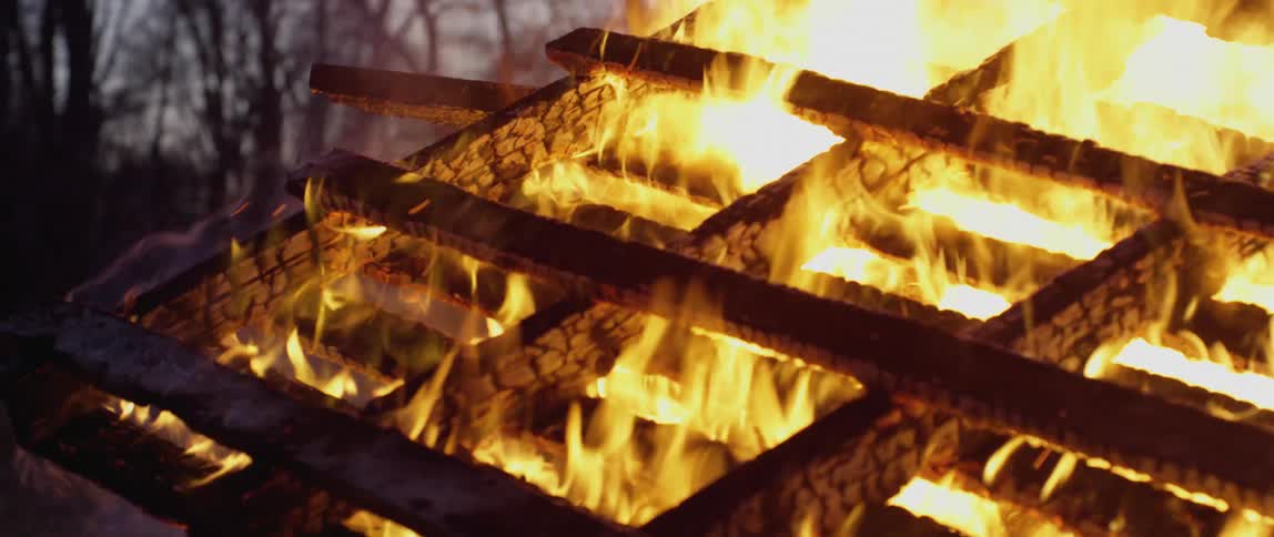 Close up of pallets of wood burning at night in the forest