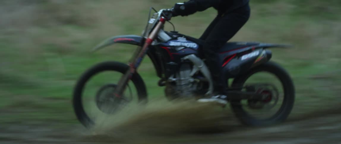 A man is dirt biking around the forest in spring