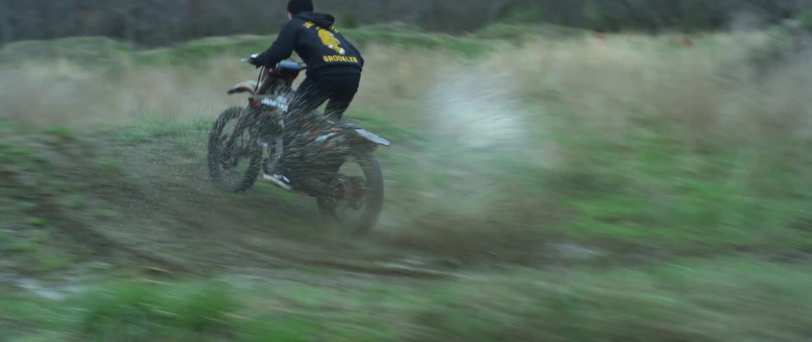 A man drives his motorbike over small jumps in a forest area