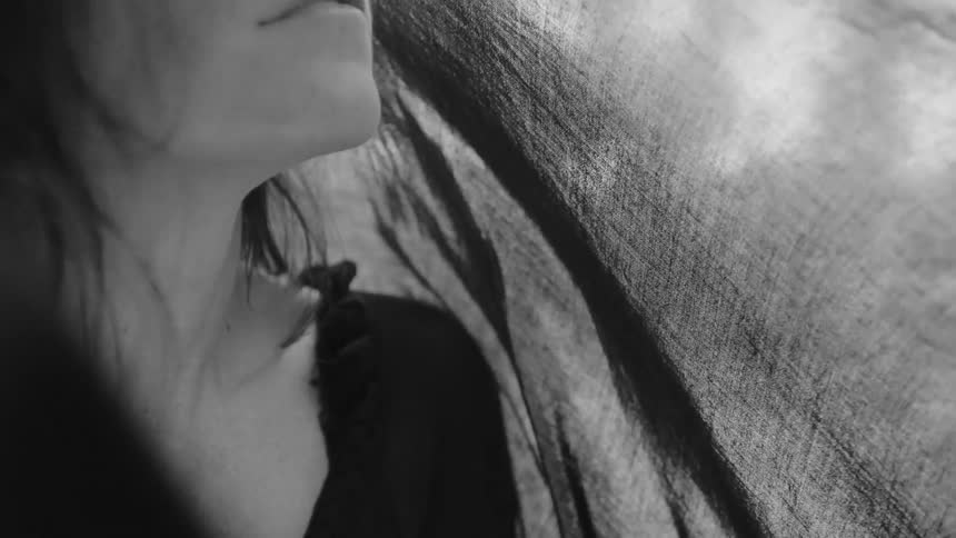 Close up of a womans face with material over it as it blows in the wind