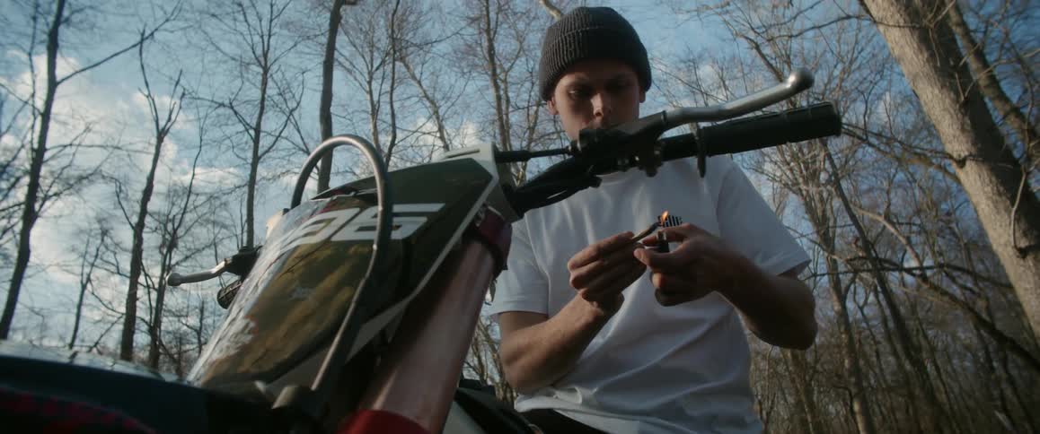 A man sitting on a dirt bike with a lighter