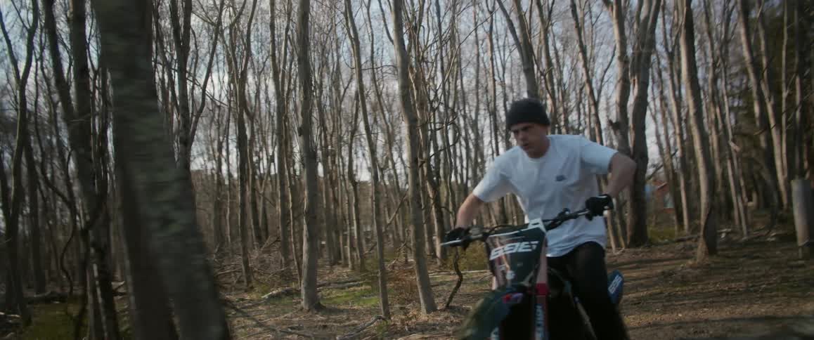 A man is riding a motorcycle through the woods