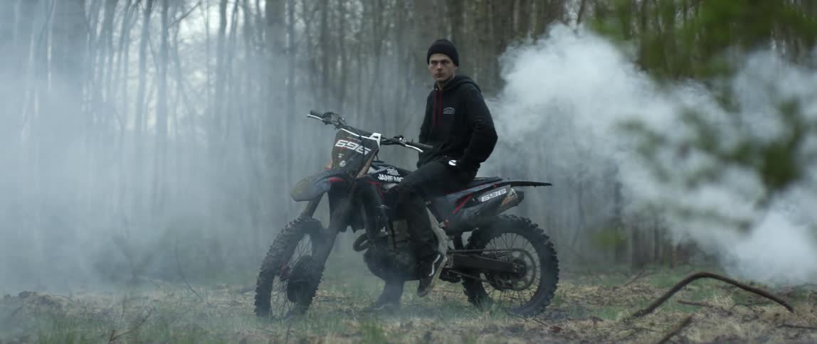 A man sitting on a dirt bike in a forest
