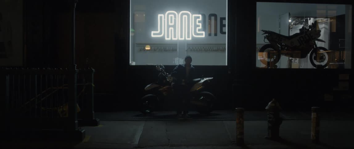 Young man sitting on a motocycle in front of a store in the city at night
