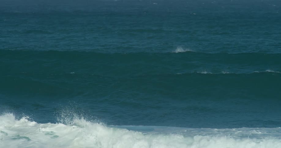 A surfer swimming over ocean waves on a surfboard