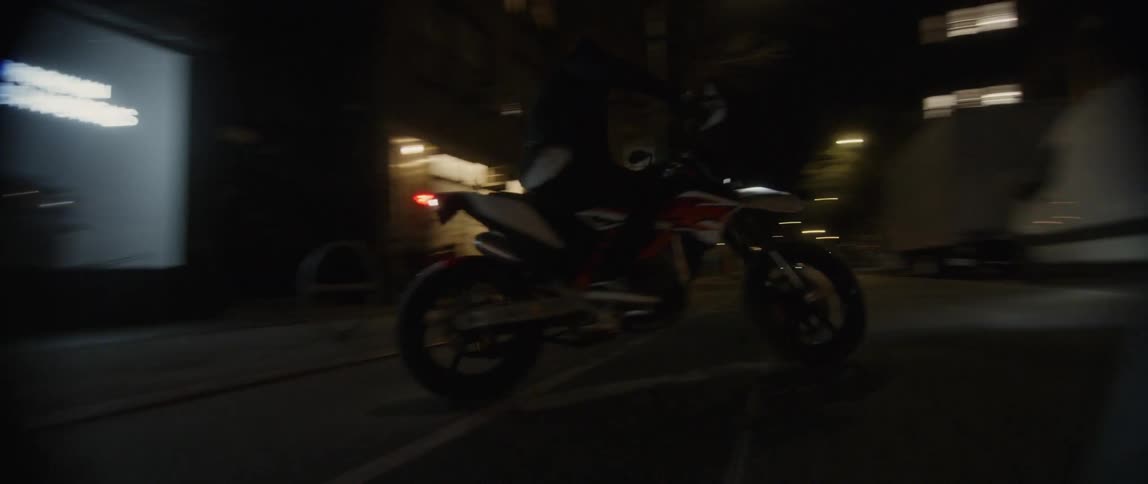 A person races out of the building door on a motorcycle
