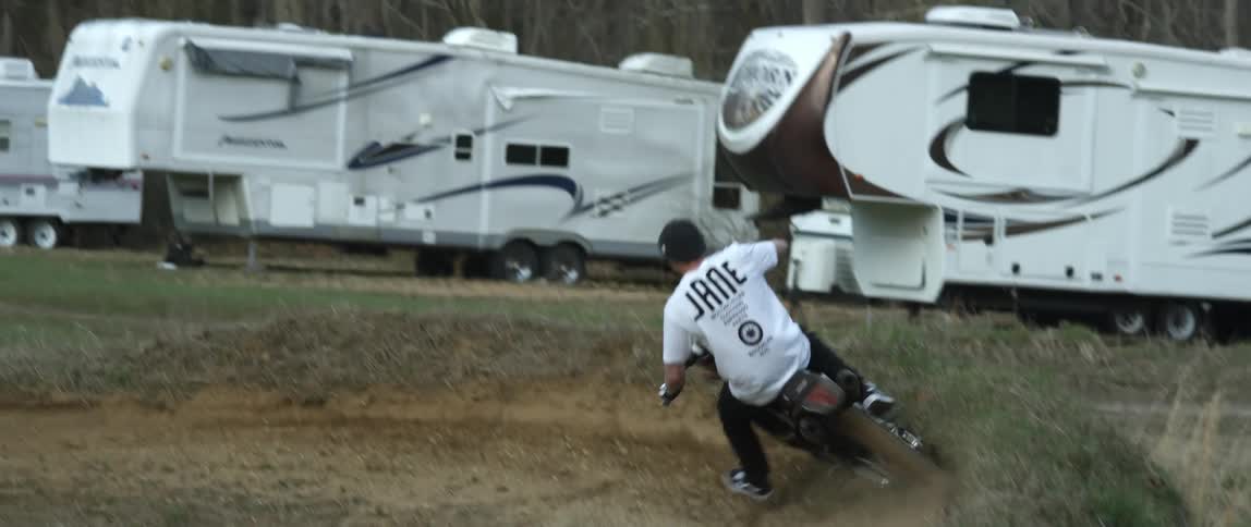 A man rides a motorcycle along an offroad motorcycle course during the day