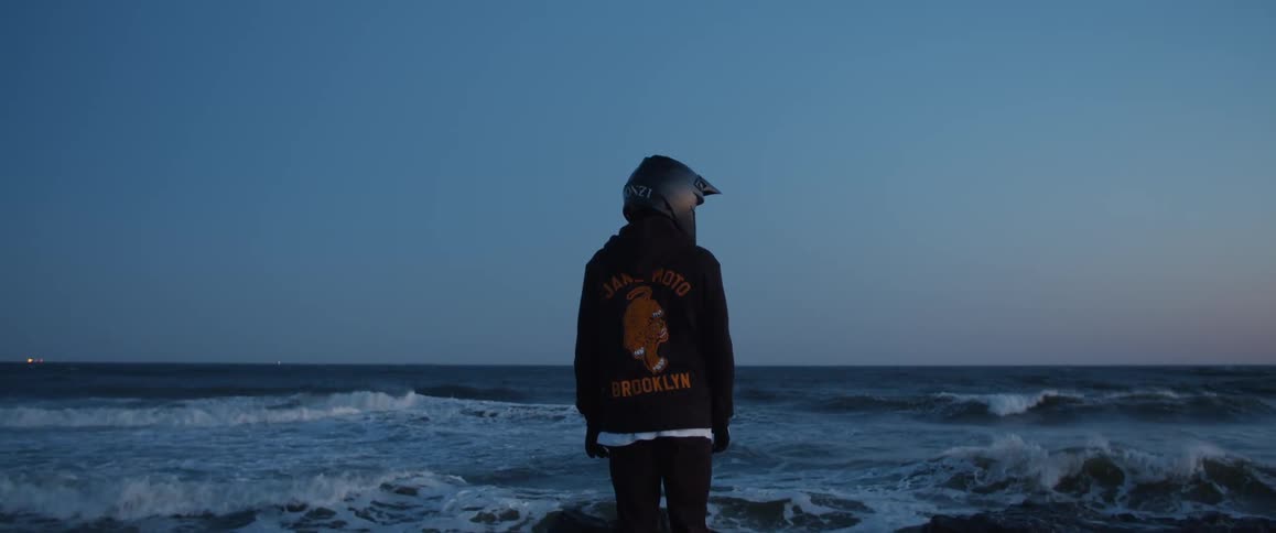 A person stands next to the rough water