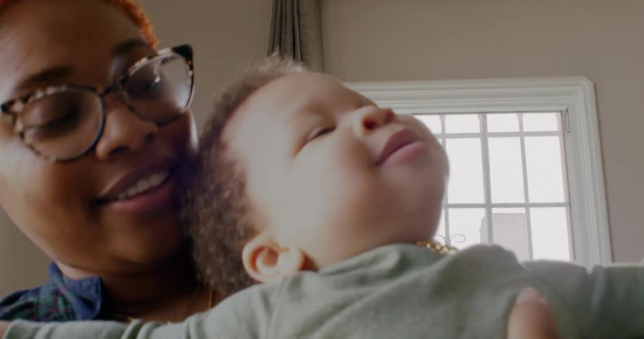 Smiling mother holds baby trying to direct his attention forward