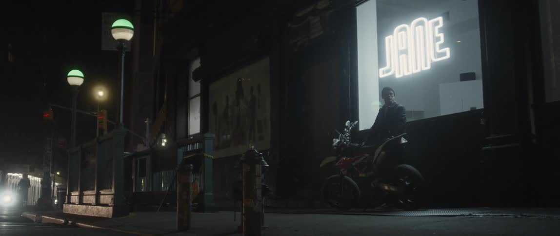 A man stands next to a shop with his motorcycle