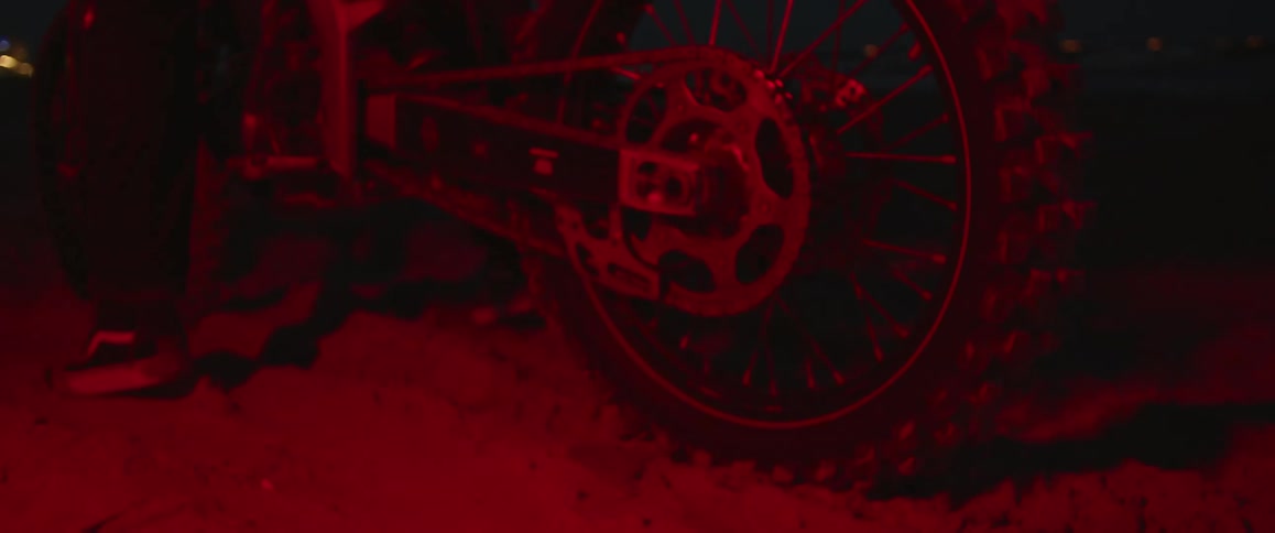 A man kicks up dirt while starting up his motorcycle