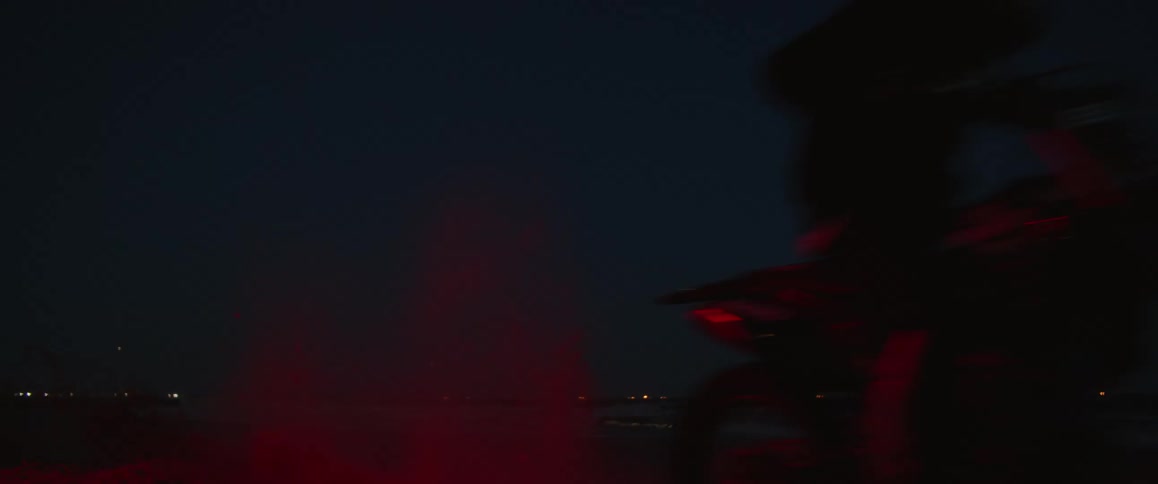 A person sitting on a motorcycle at night drives away