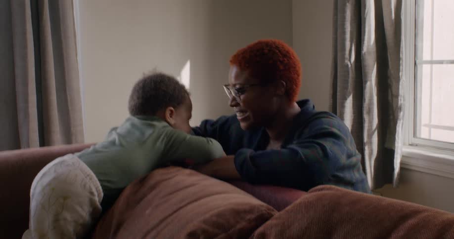 A mother kissing her baby on the forehead while playing in a living room