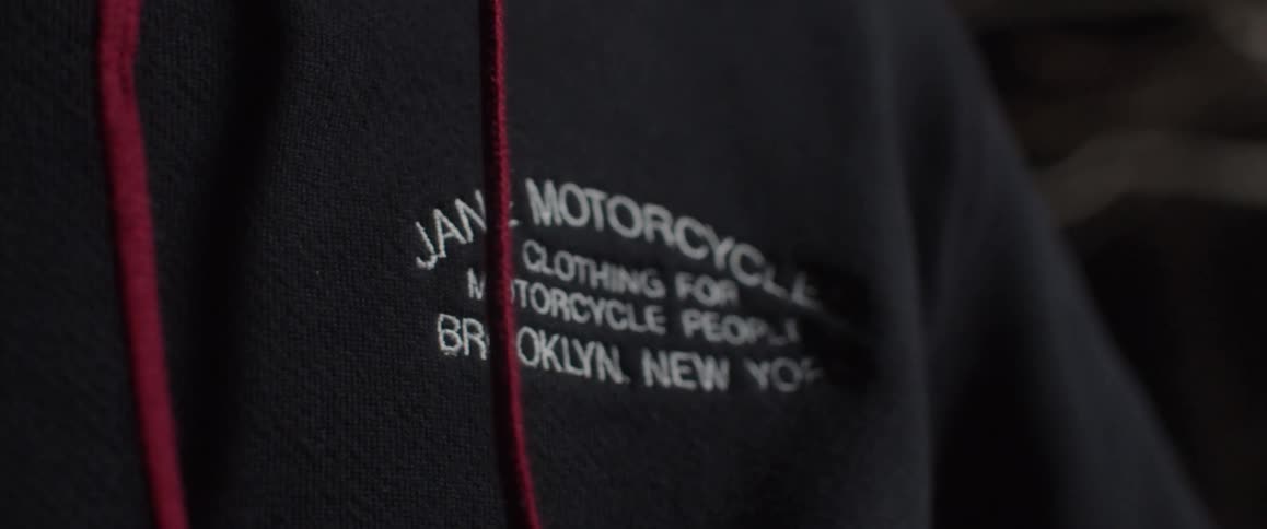 A man stands in a garage wearing a shirt for a motorcycle club