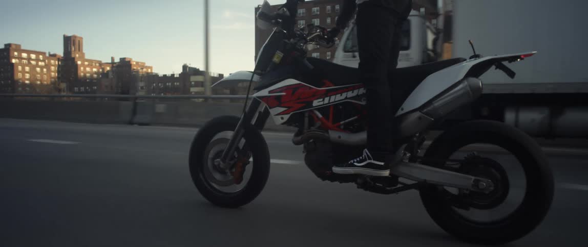 Motorcyclist stands on motorcycle while riding along highway among other vehicles