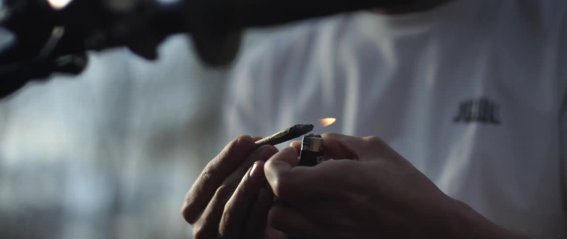 Someone is holding a blunt and putting a flame to it with a lighter