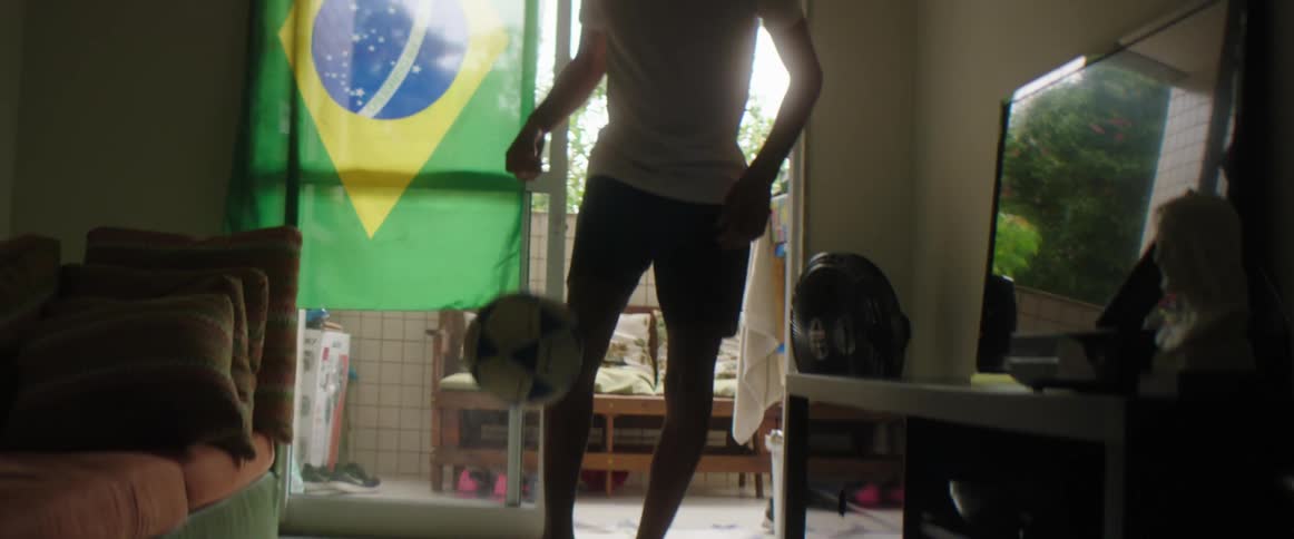 A young male foot dribbles a soccer ball inside a home