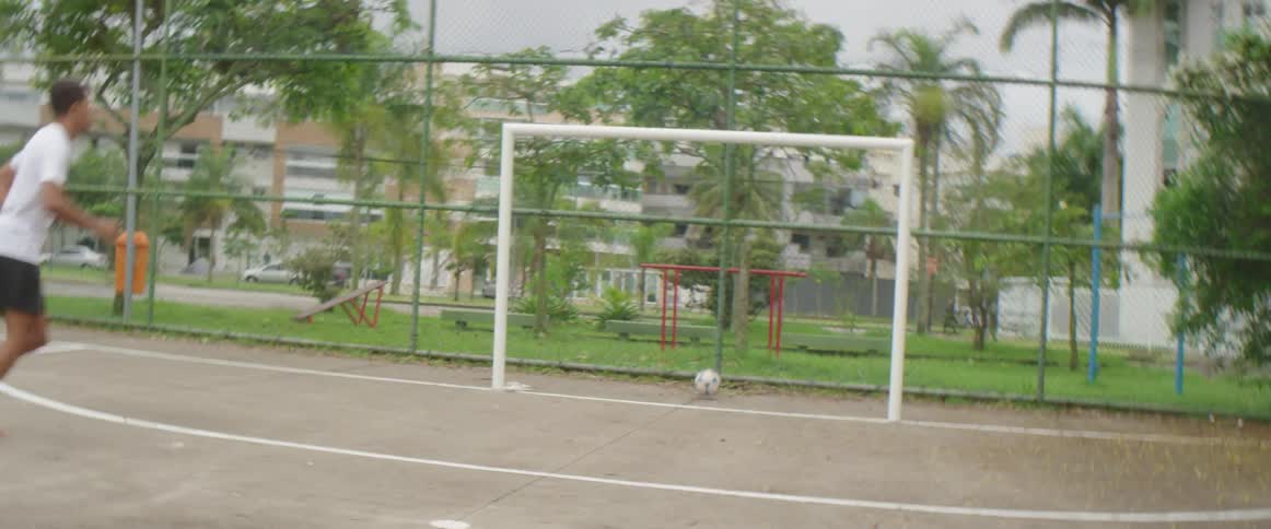 A man is playing soccer at a public park in spring
