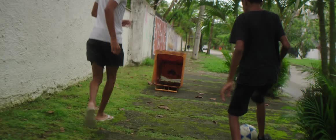 Two youths play soccer using box as a goal