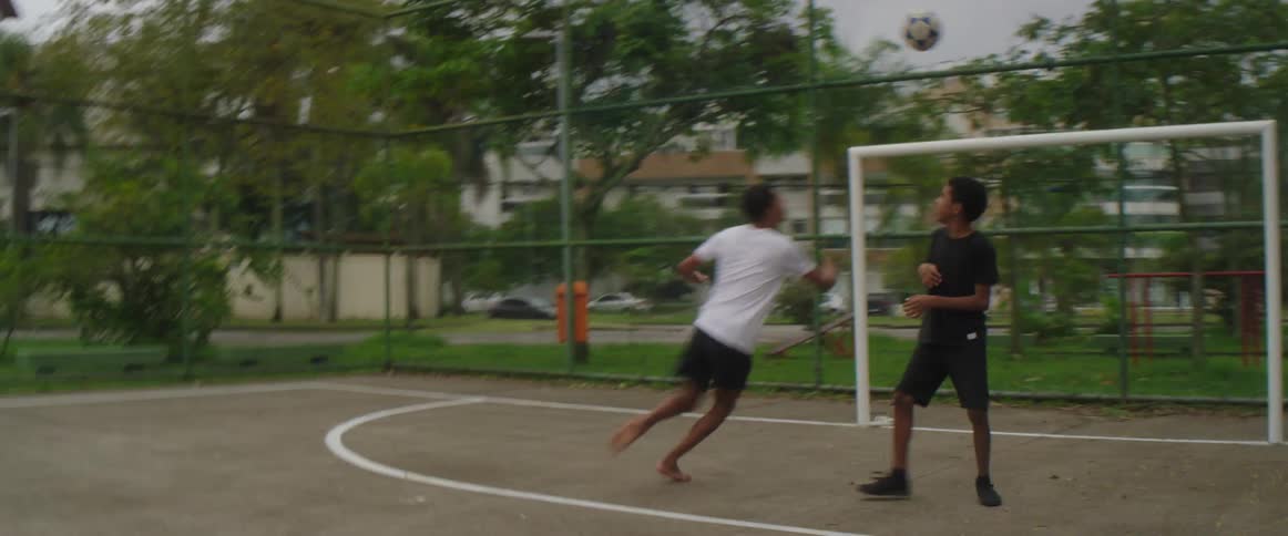Two friends are playing soccer at a park against each other