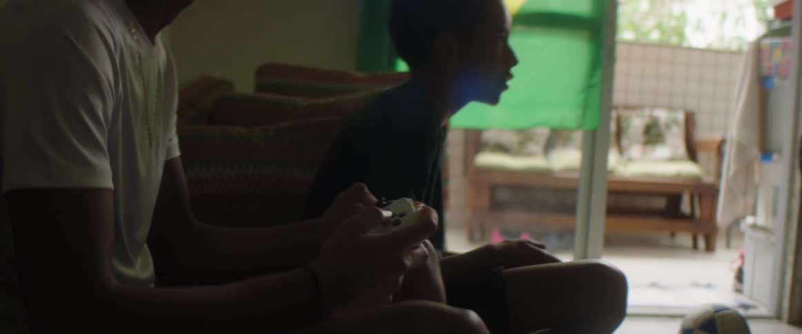 A man and boy sit together with video game controllers and get excited
