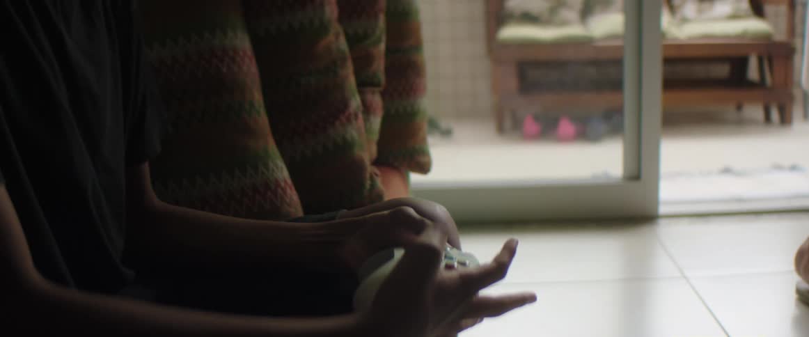 Boy with blue t shirt sits on couch and plays video games in the living room at home