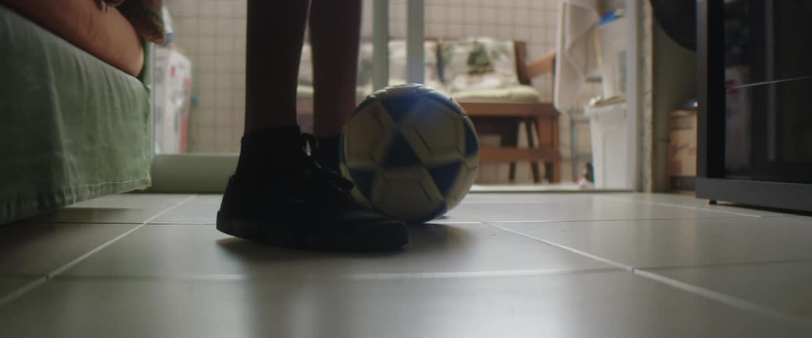 A boy is dribbling a soccer ball indoors during the day