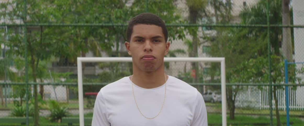 A male teen is standing by a soccer court in spring