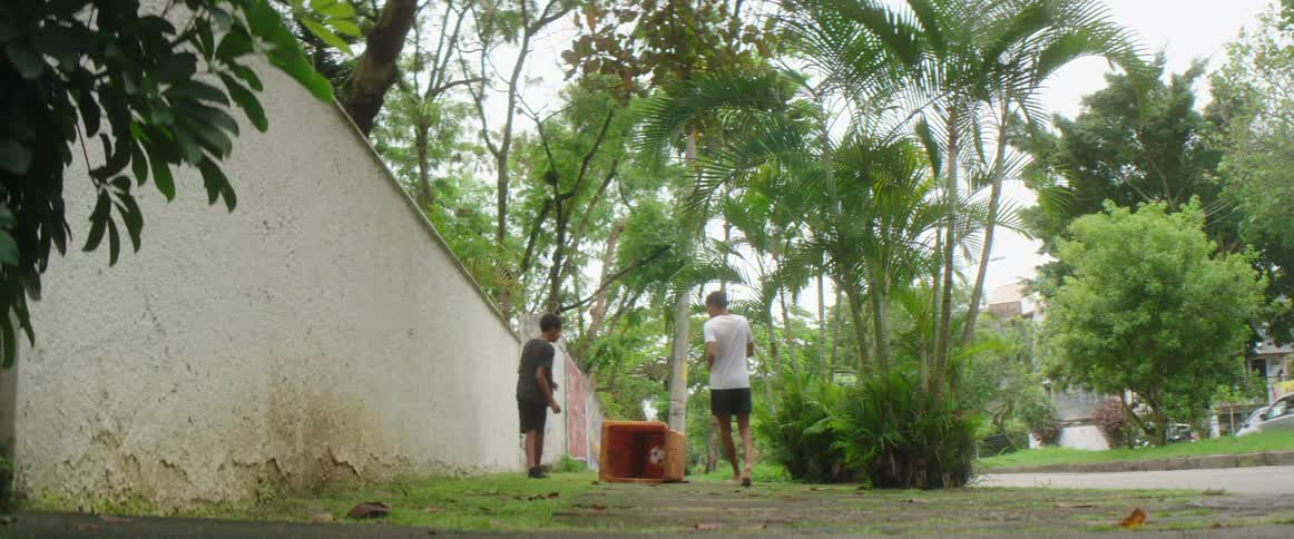 Two young friends playing with a soccer ball on the sidewalk near the street