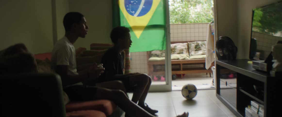 A teenage boy and his younger brother play a video game at home together