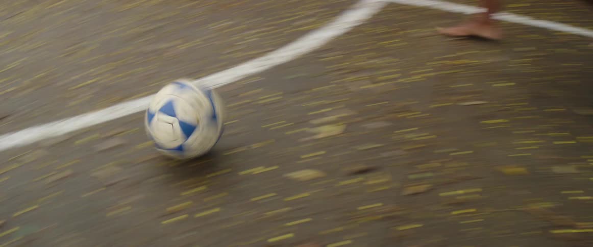 A boy kicks a soccer ball through another boys legs and makes a goal