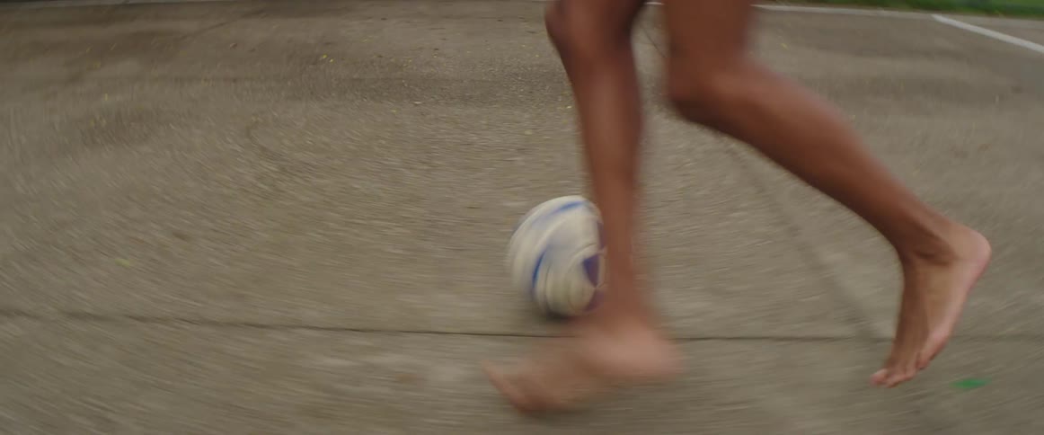 A boy runs along while kicking a soccer ball