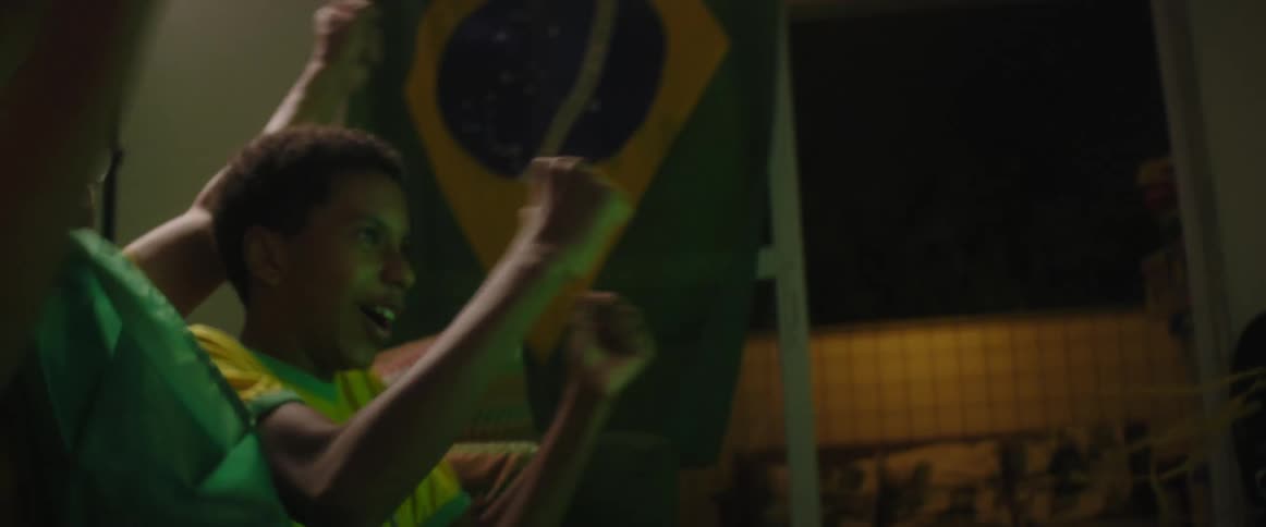 A father sits with his two sons as they watch a game and then they cheer and hug