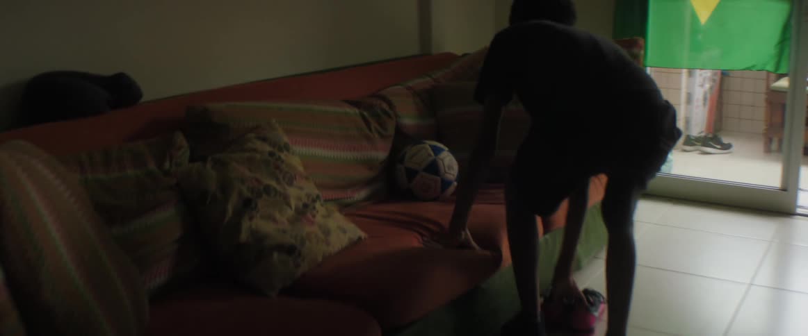 Young boy picks up a soccer ball from the couch and leaves the apartment in a hurry