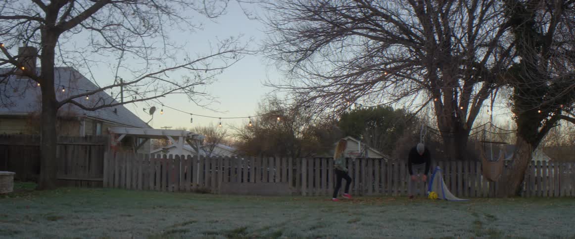 Dad pulls the soccer ball out the net and tosses it back for his daughter to kick
