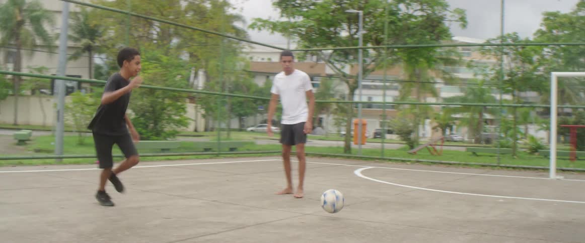 Friends practice soccer on a field inside a park on the city